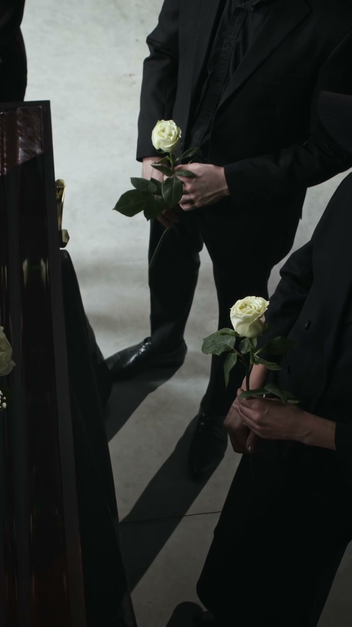 Solemn Mourners Holding White Roses at Funeral