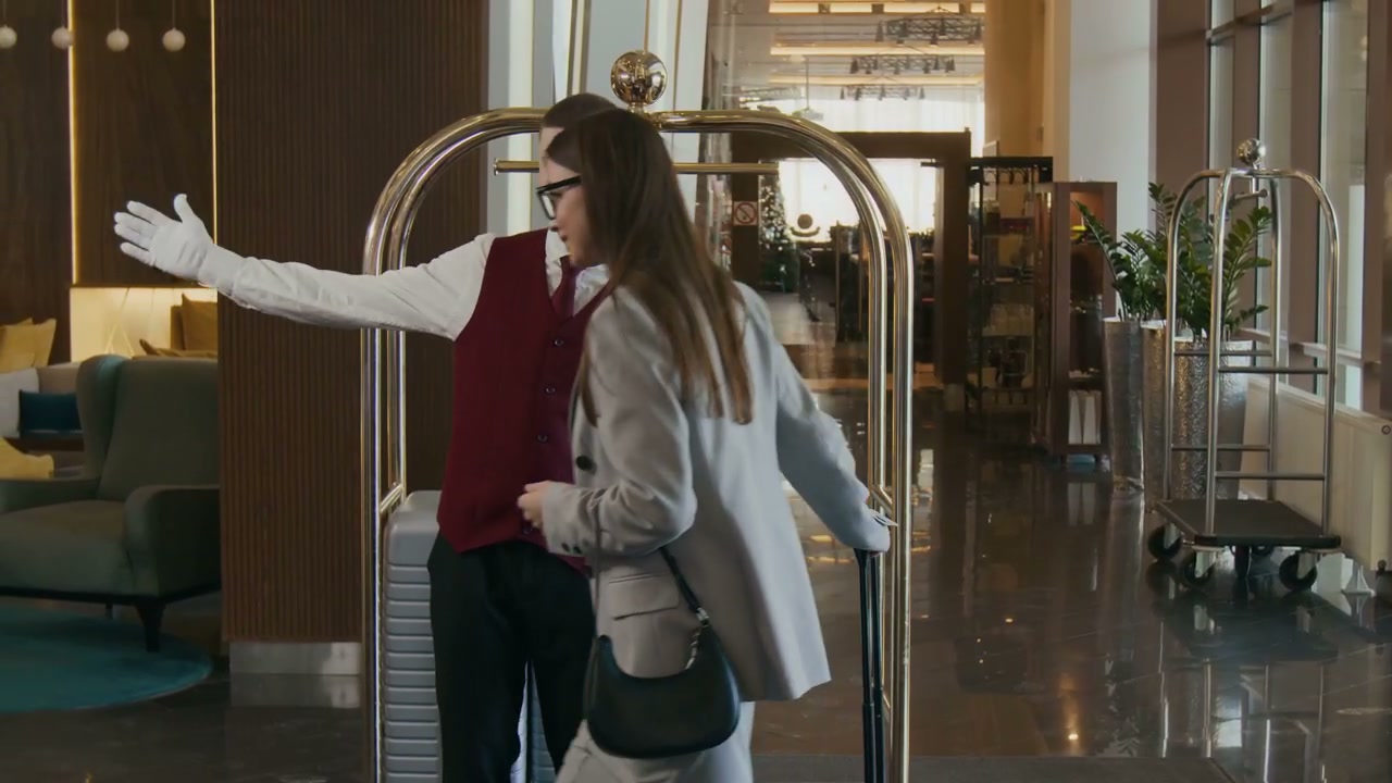 Bellhop Assists Guest with Luggage in Hotel