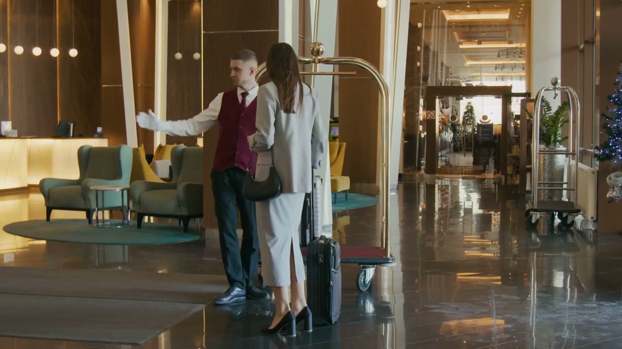 Bellhop Greets Guest and Takes Luggage in Hotel Lobby