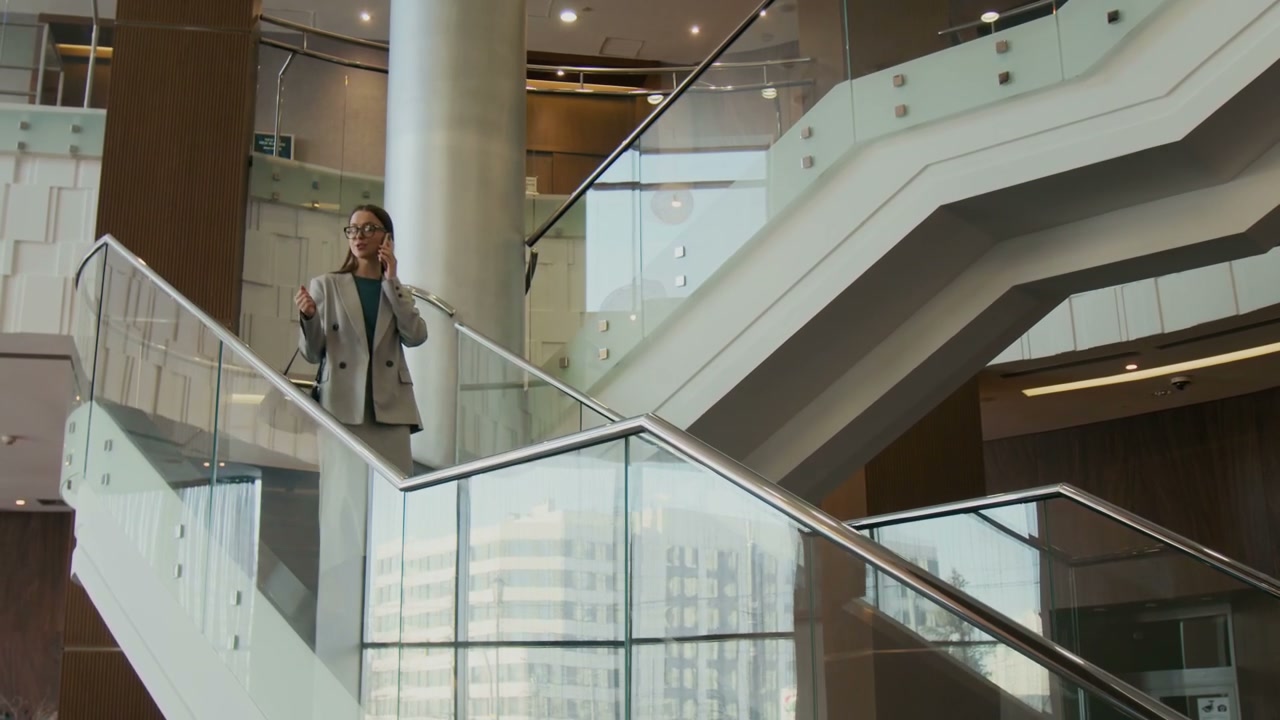 Smiling Businesswoman on Phone Descending Hotel Stairs