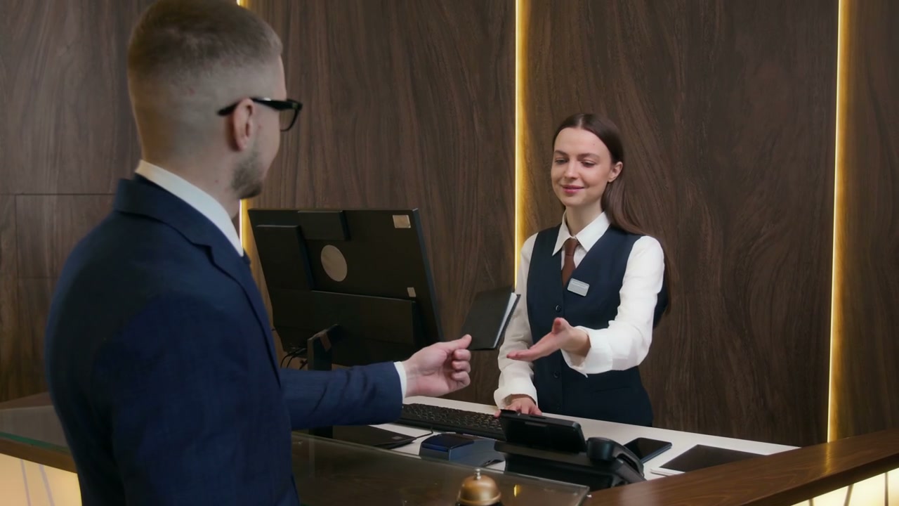 Man Checking In at Hotel Reception Desk