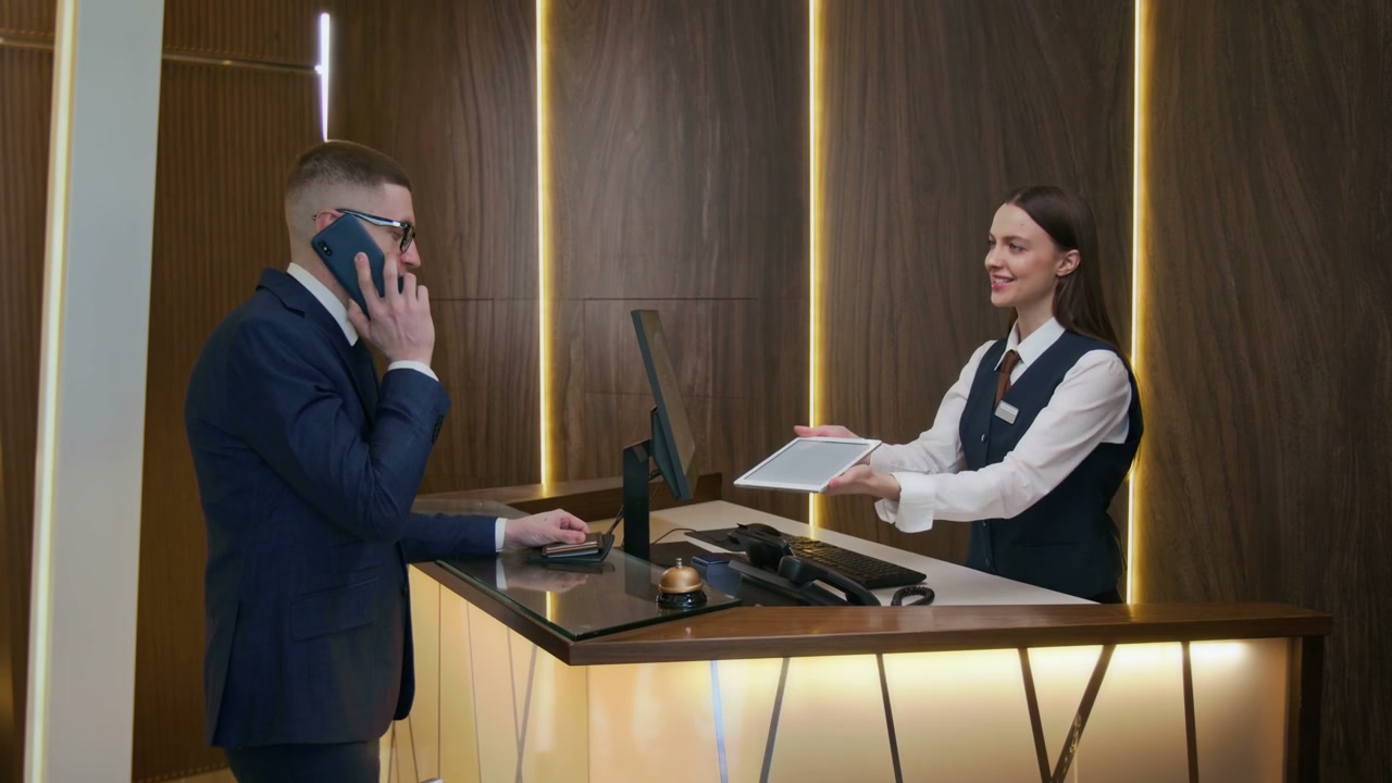 Businessman Signs Tablet at Hotel Reception Desk