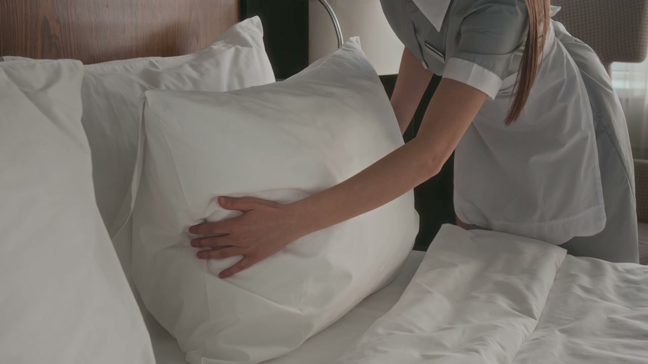 Hotel Maid Arranging Pillows on Bed