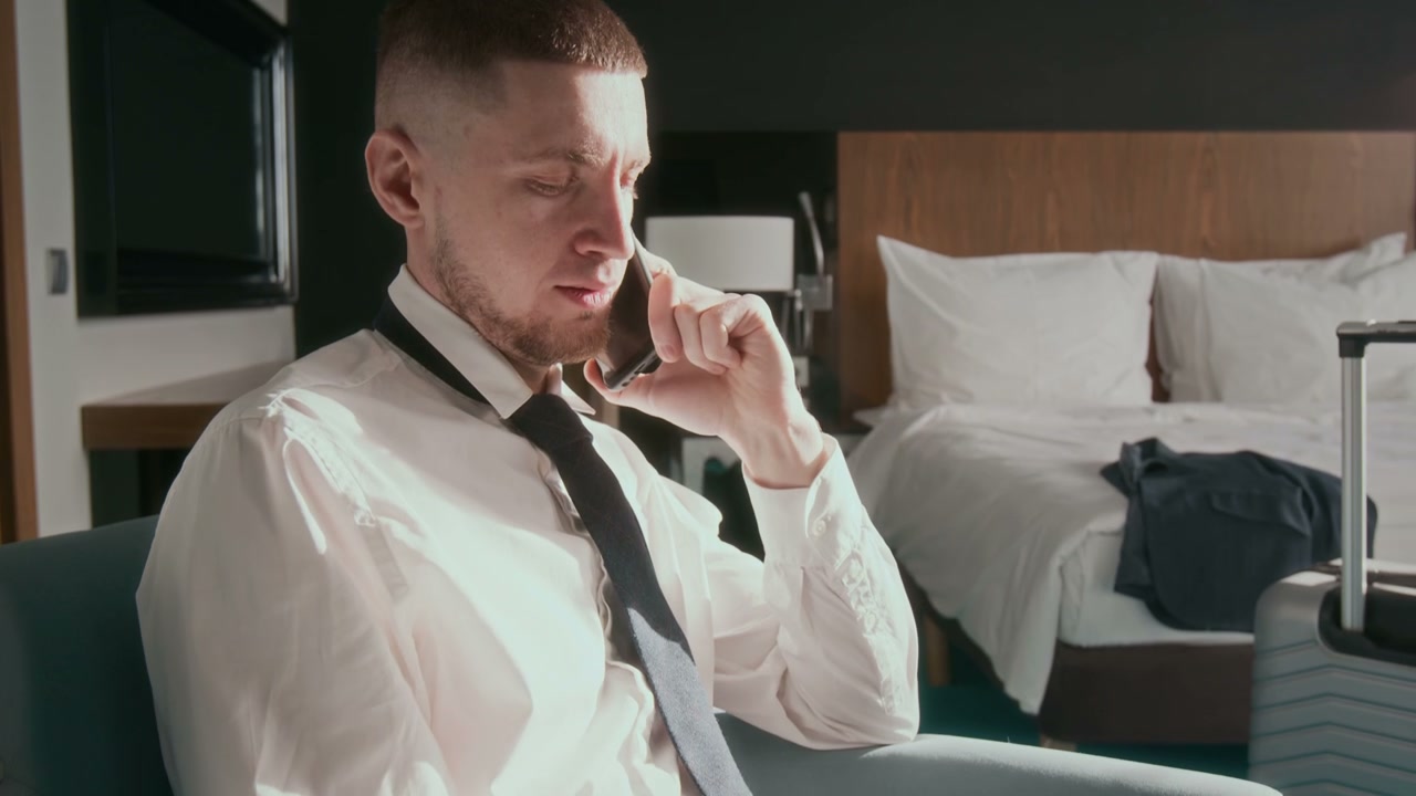 Man Working on Laptop and Phone in Hotel Room
