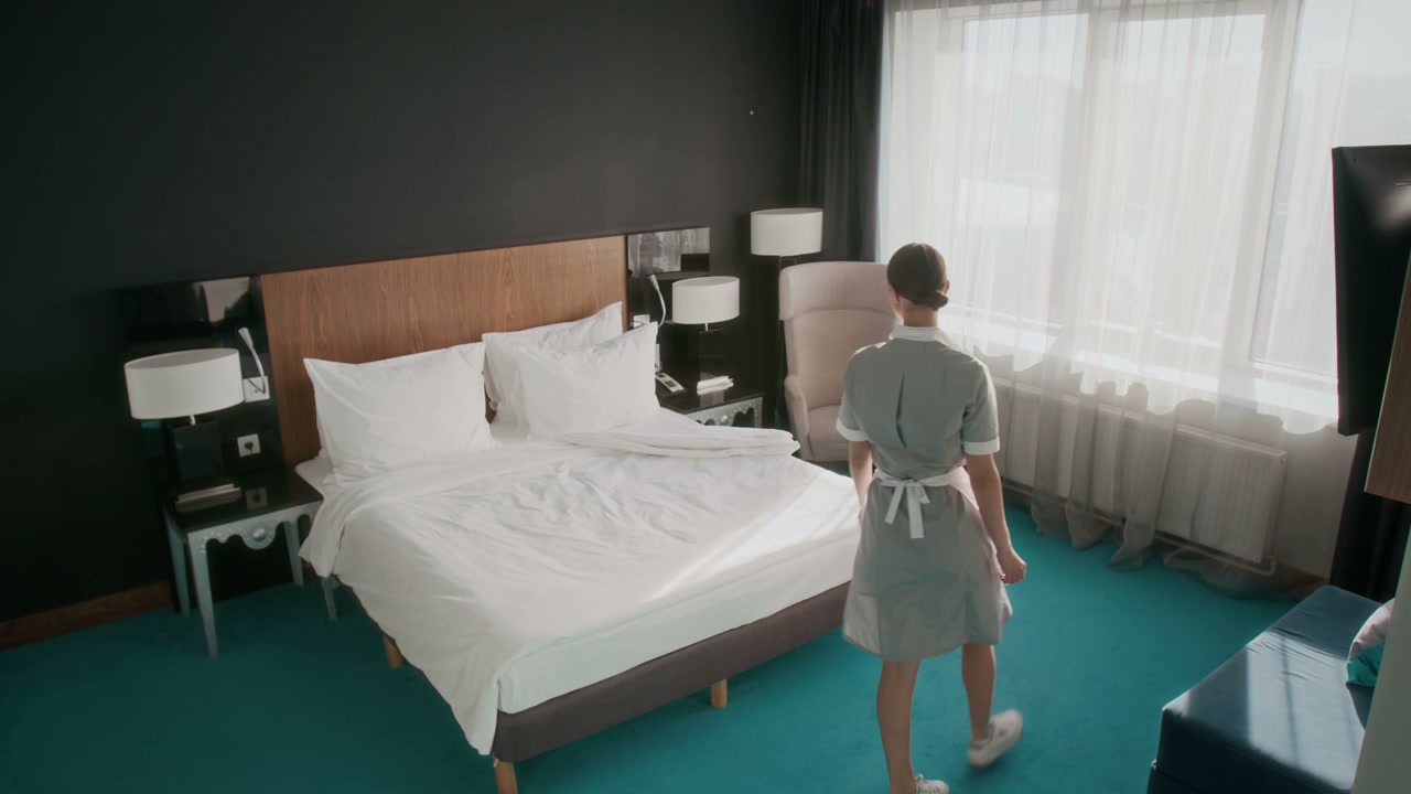 Housekeeper Making Bed in Hotel Room