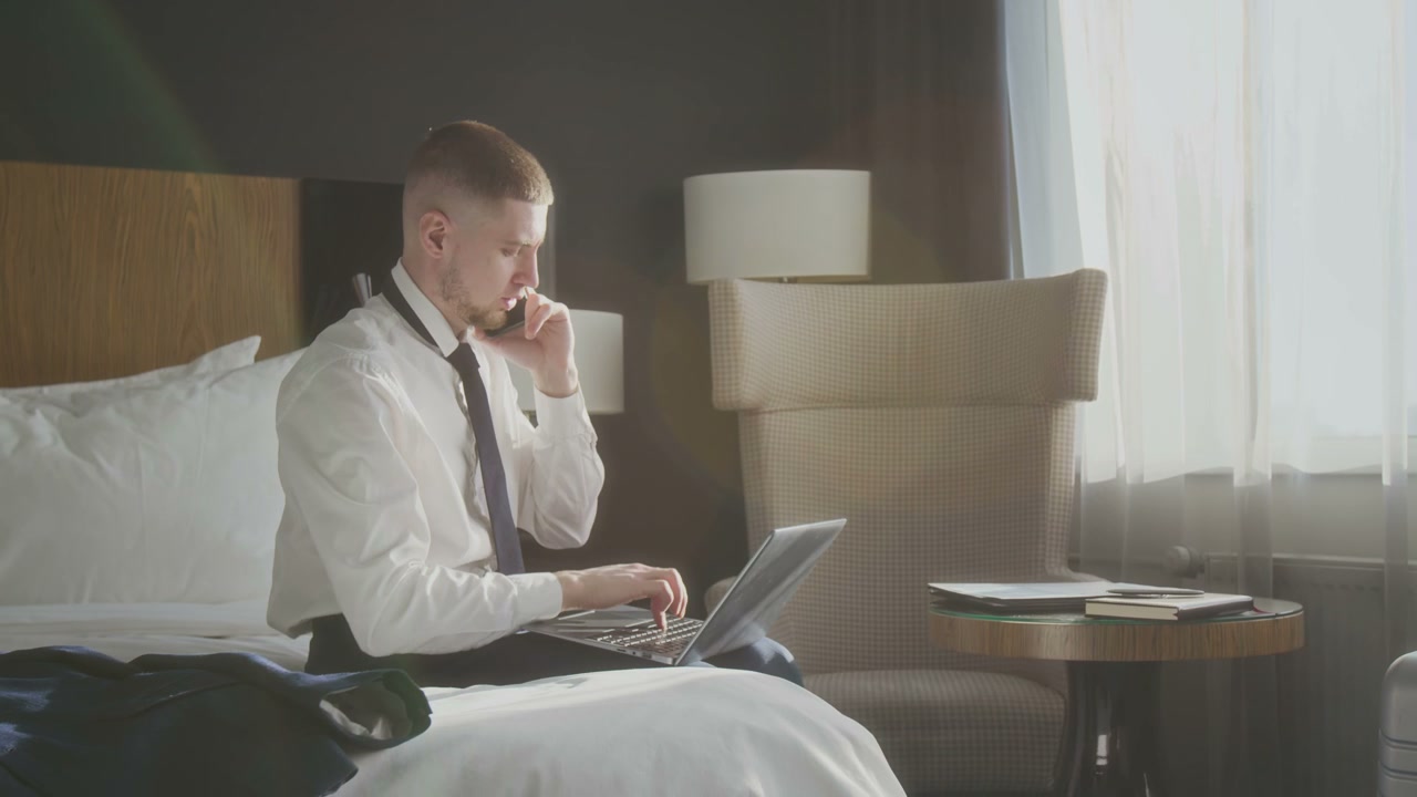 Businessman Talking on Phone and Working in Hotel