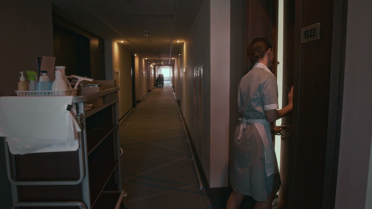 Hotel Housekeeper Enters Room With Cleaning Cart