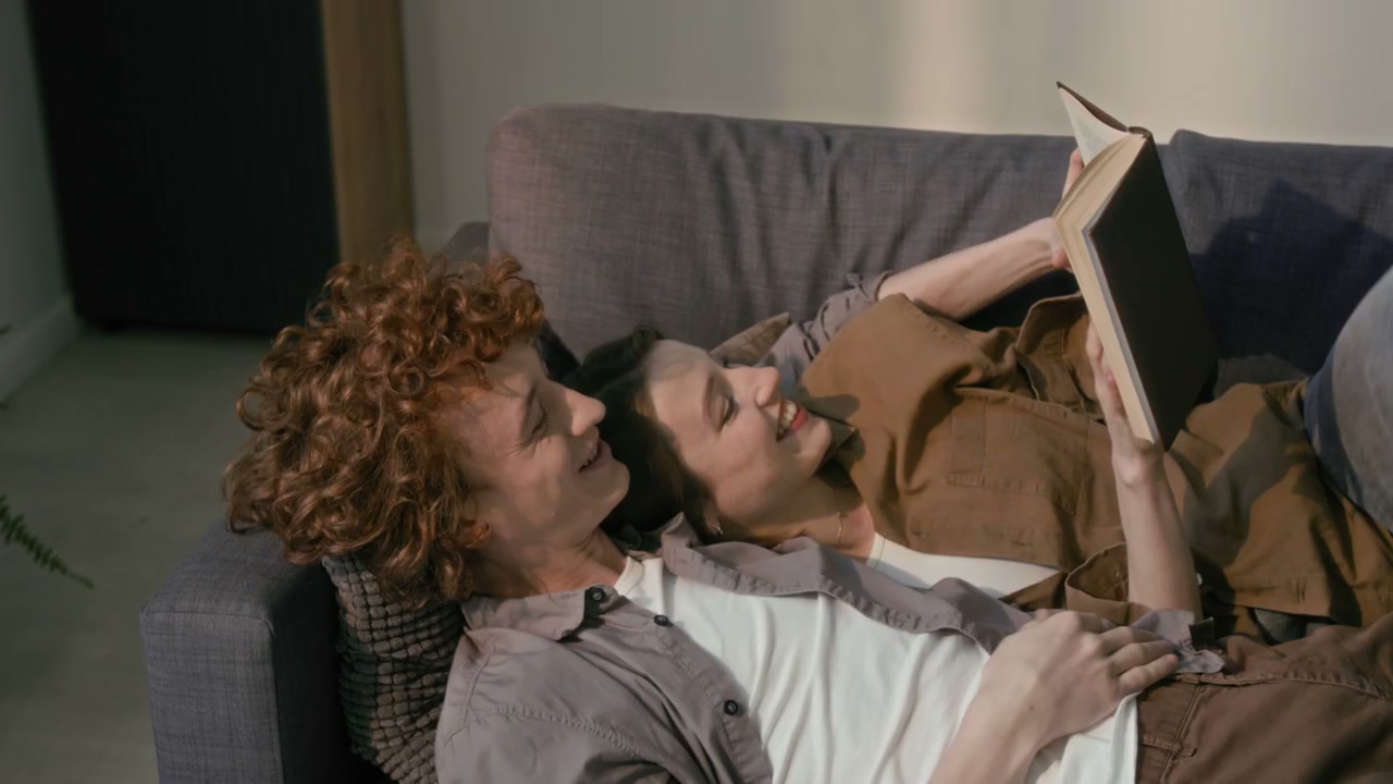 Young Couple Reading Book on Sofa