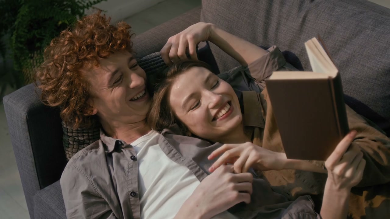 Happy Couple Laughing While Reading a Book