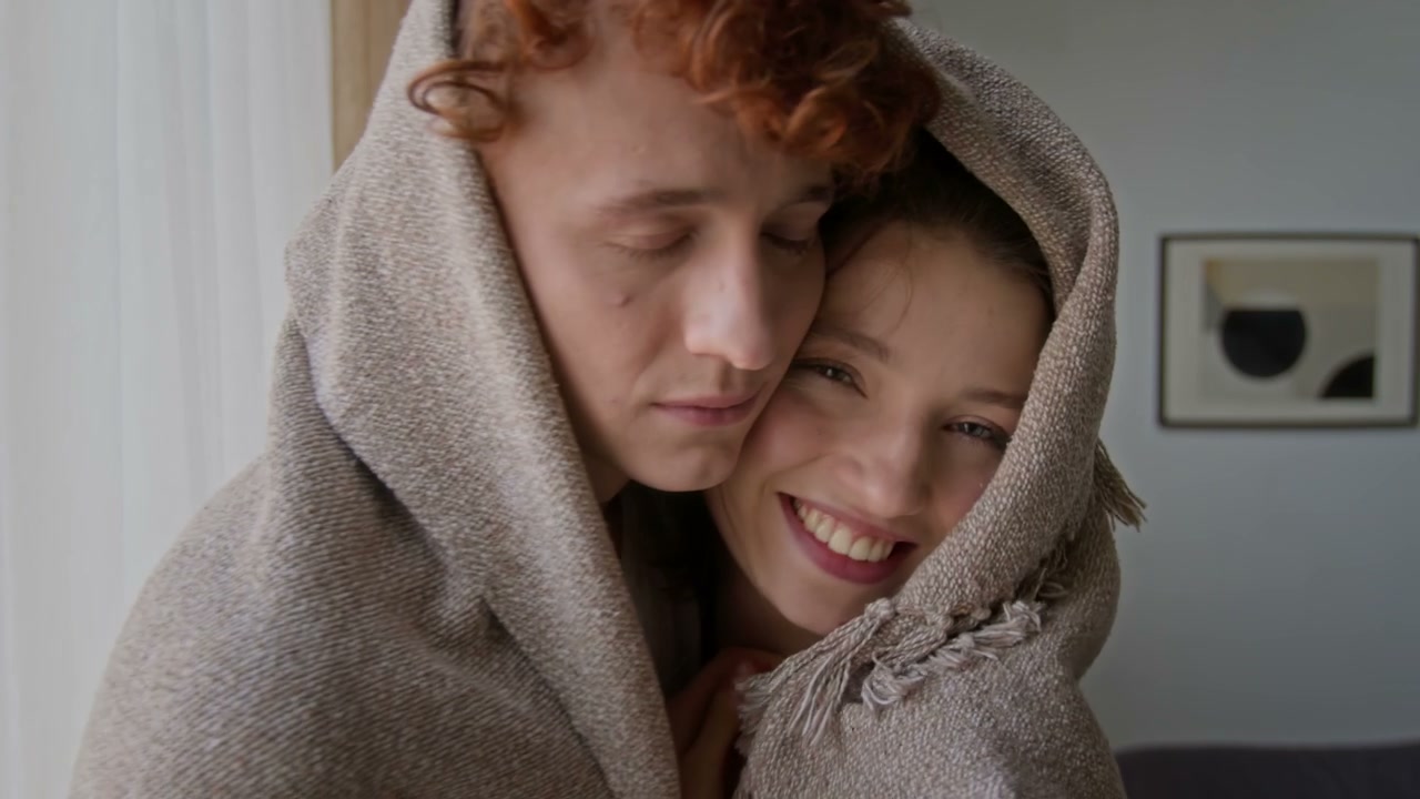 Romantic Couple Embracing in a Blanket at Home