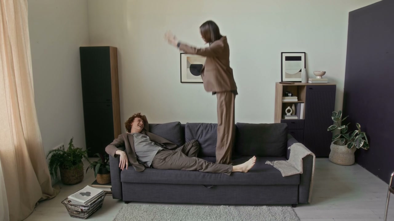 Playful Couple Jumping on Sofa at Home