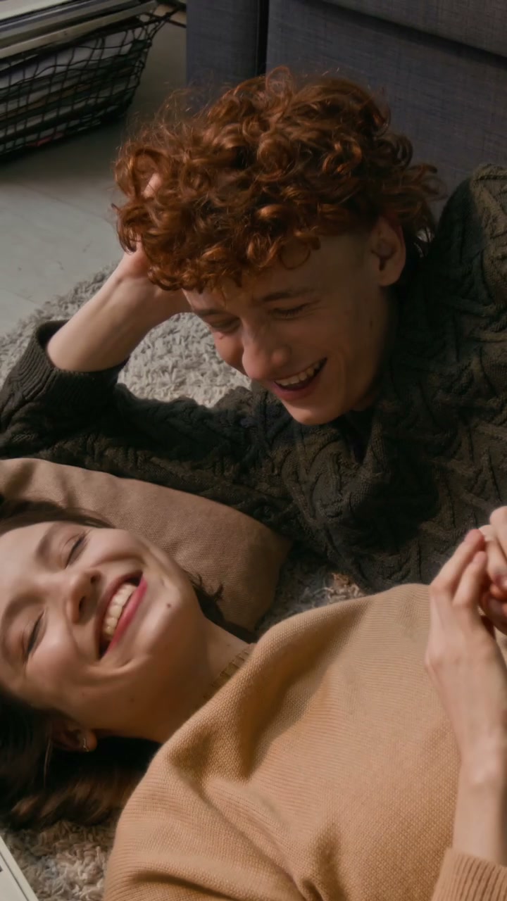 Happy Young Couple Laughing on Floor at Home