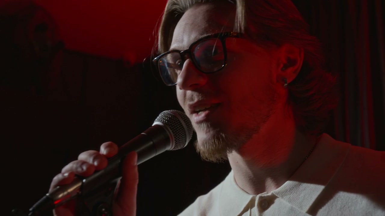 Male Performer Speaking into Microphone on Stage