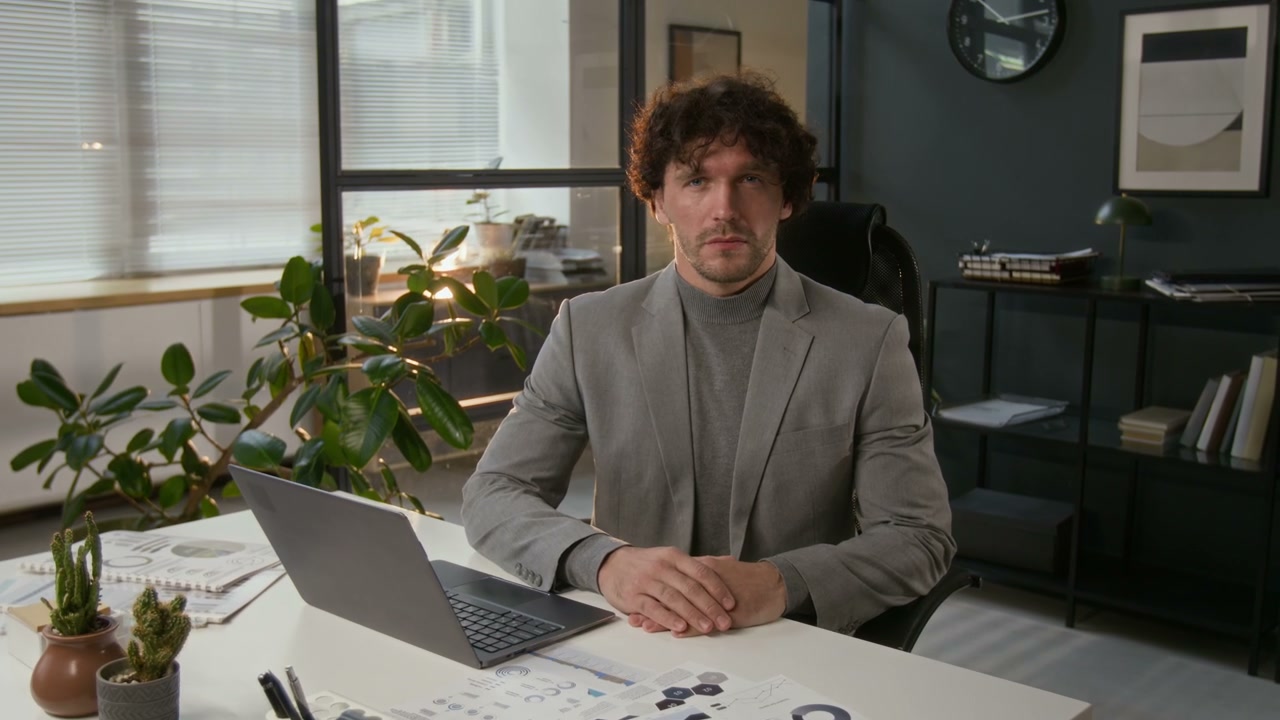 Businessman Looking at Camera at Office Desk