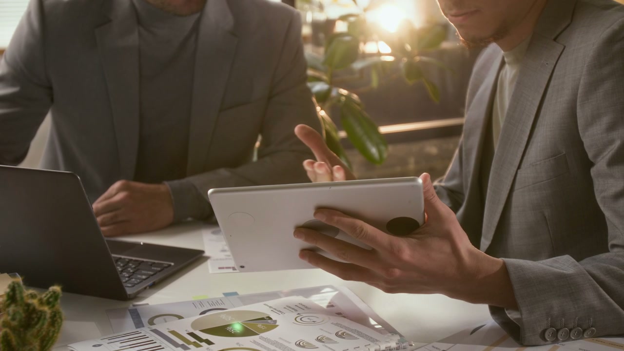 Businessmen Discussing Data on Tablet