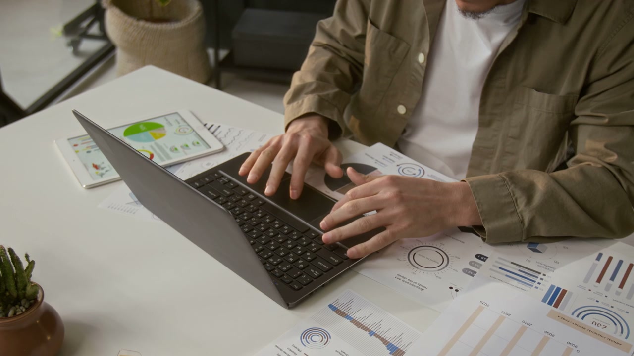 Man Working on Laptop with Business Reports
