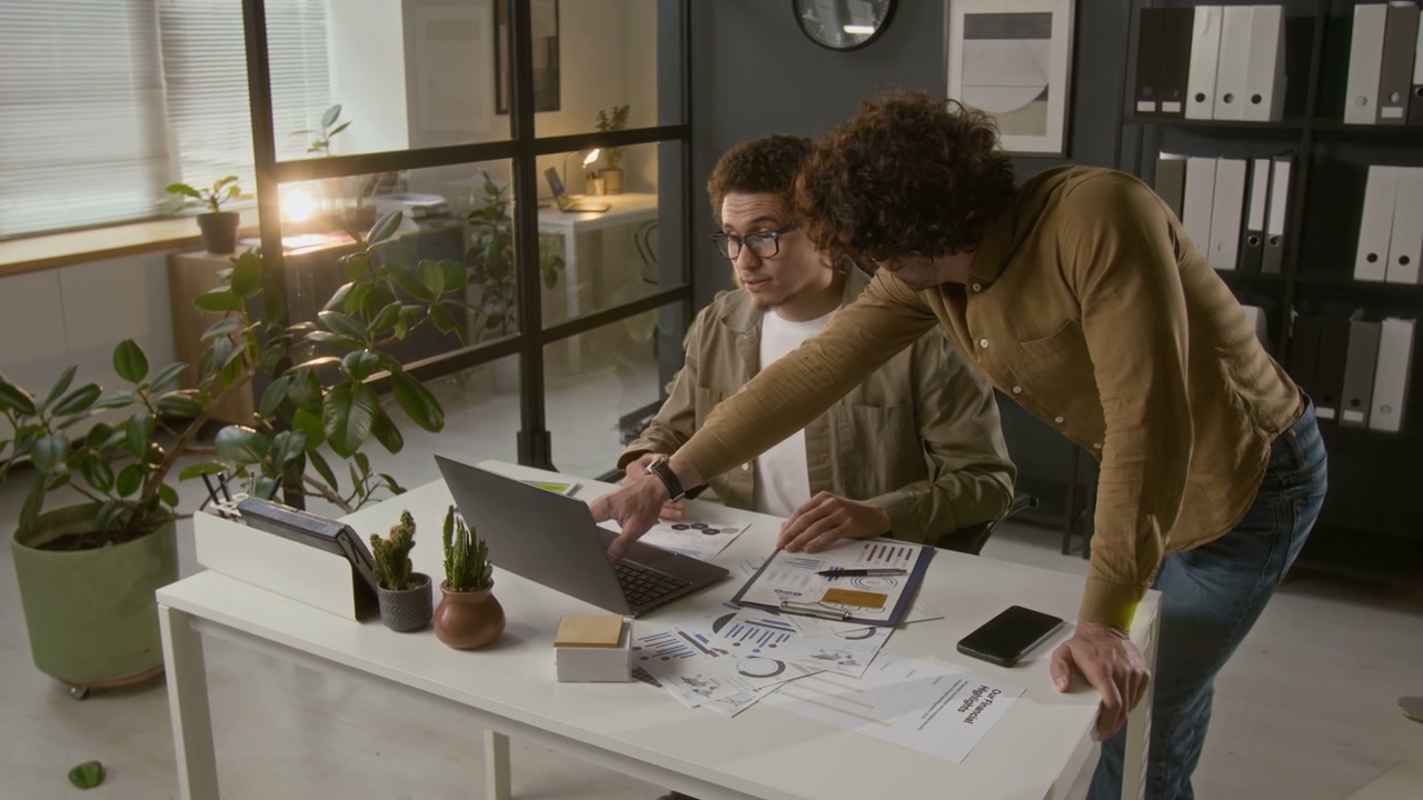 Two Men Discussing Data on Laptop in Office