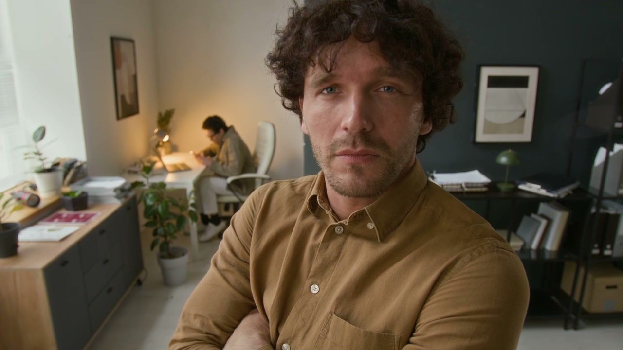 Confident Businessman Looks at Camera in Office