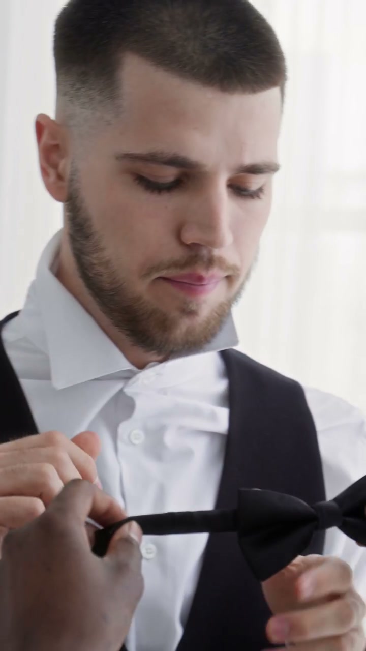 Groom Getting Help with Bow Tie on Wedding Day