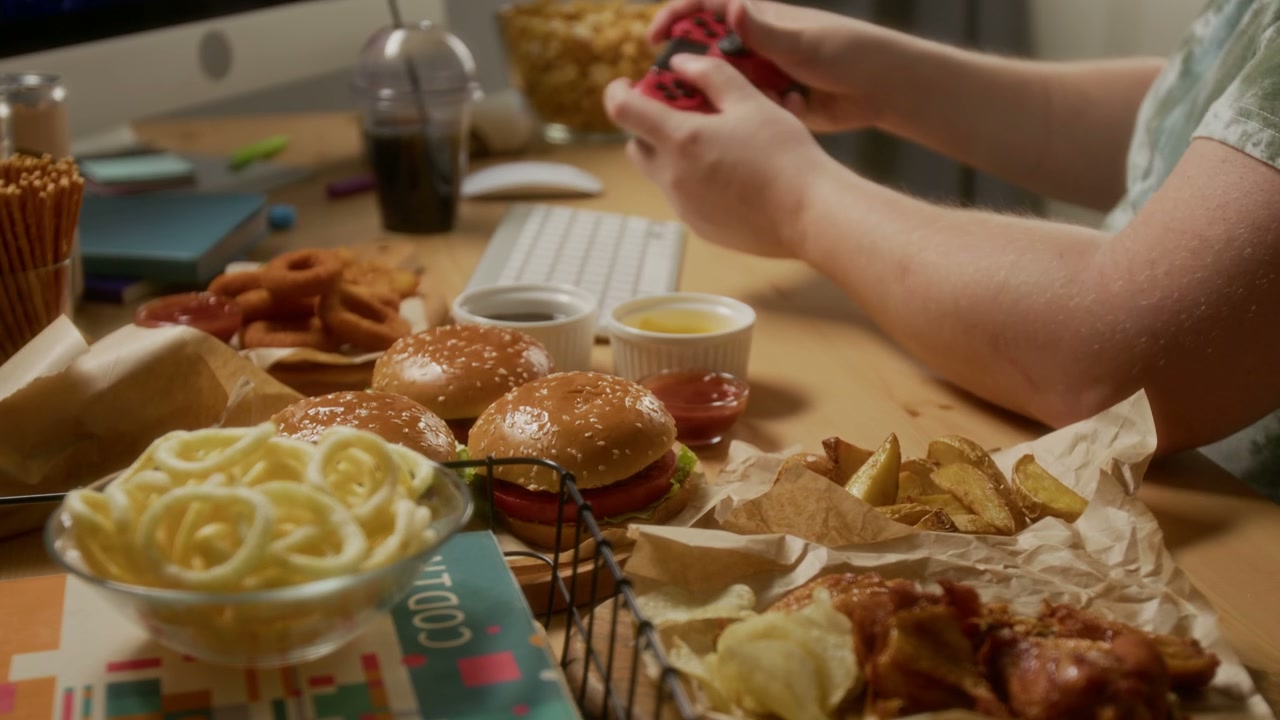 Gamer Playing Video Game Surrounded By Fast Food