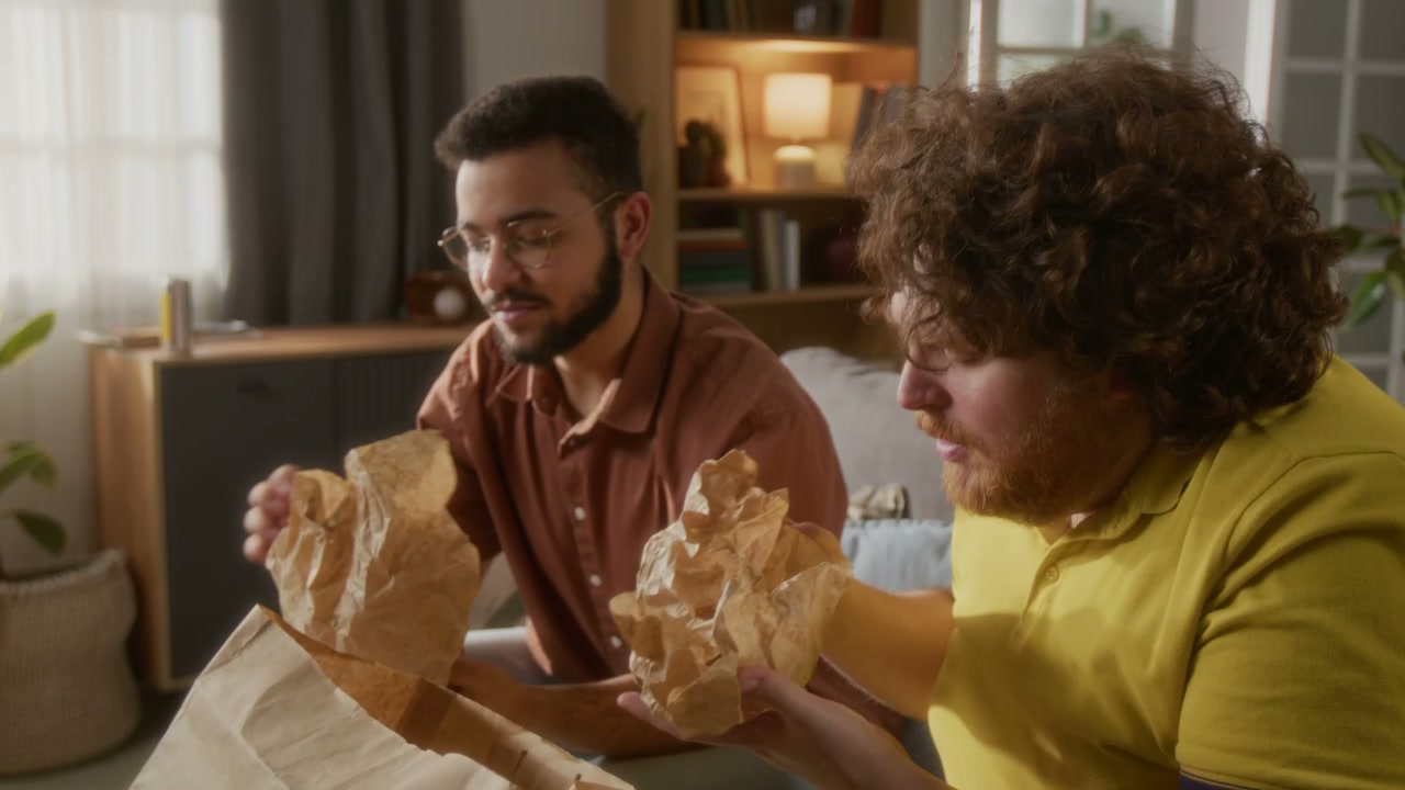 Men Unpacking Fast Food Burgers At Home
