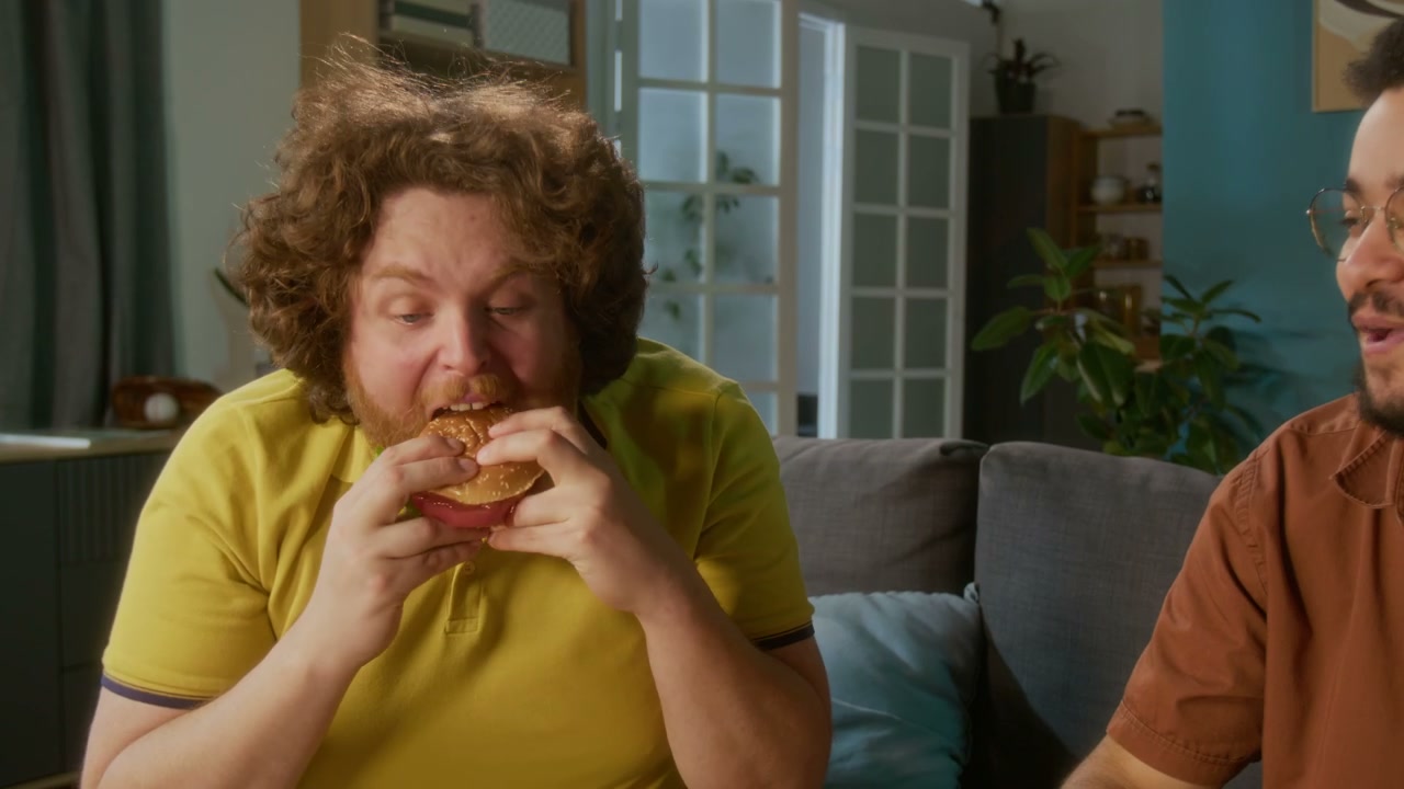 Man Devours Burger with Friend at Home