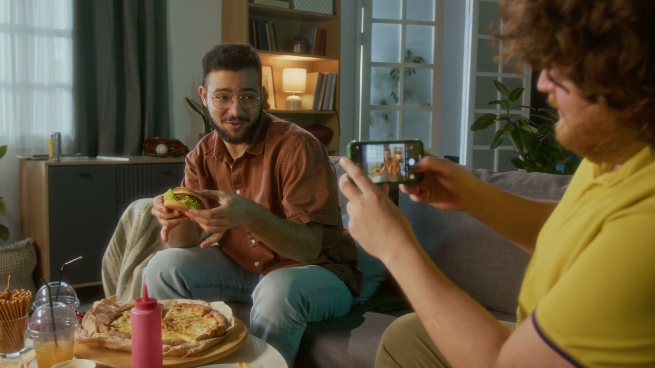 Man Photographing Friend Eating Burger