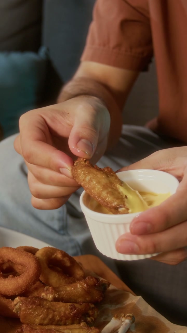 Person Dipping Chicken Wing into Sauce