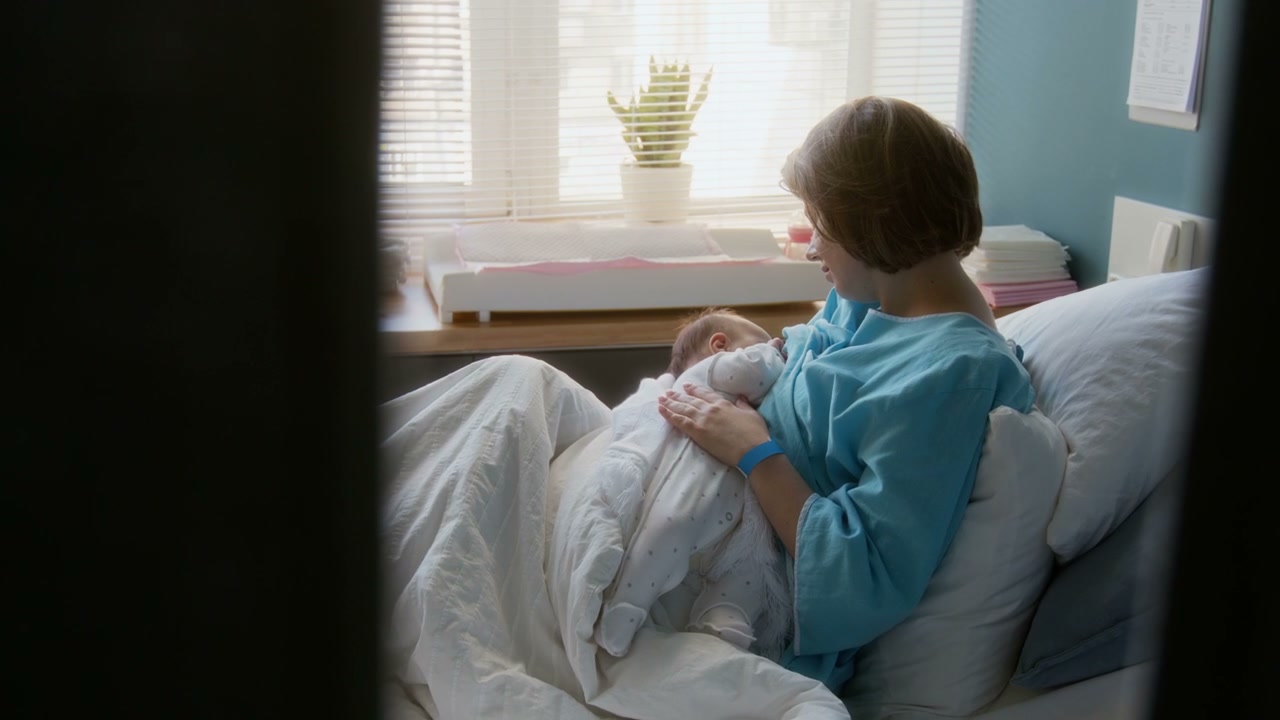 Mother Breastfeeding Newborn in Hospital Bed