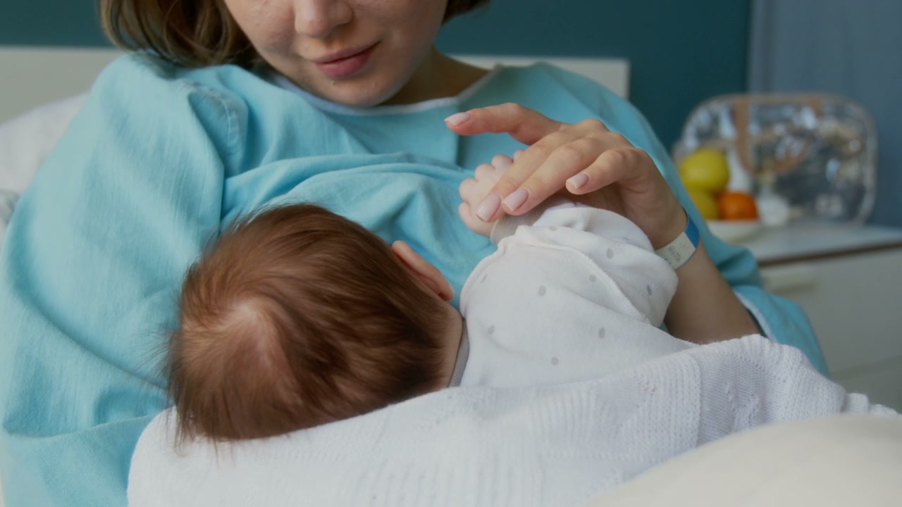 Mother Breastfeeding Newborn Baby in Hospital