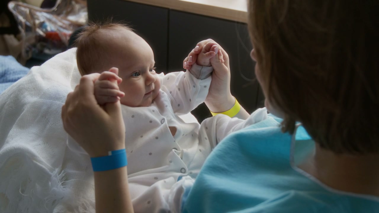 Mother Holding Newborn Baby's Hands in Hospital