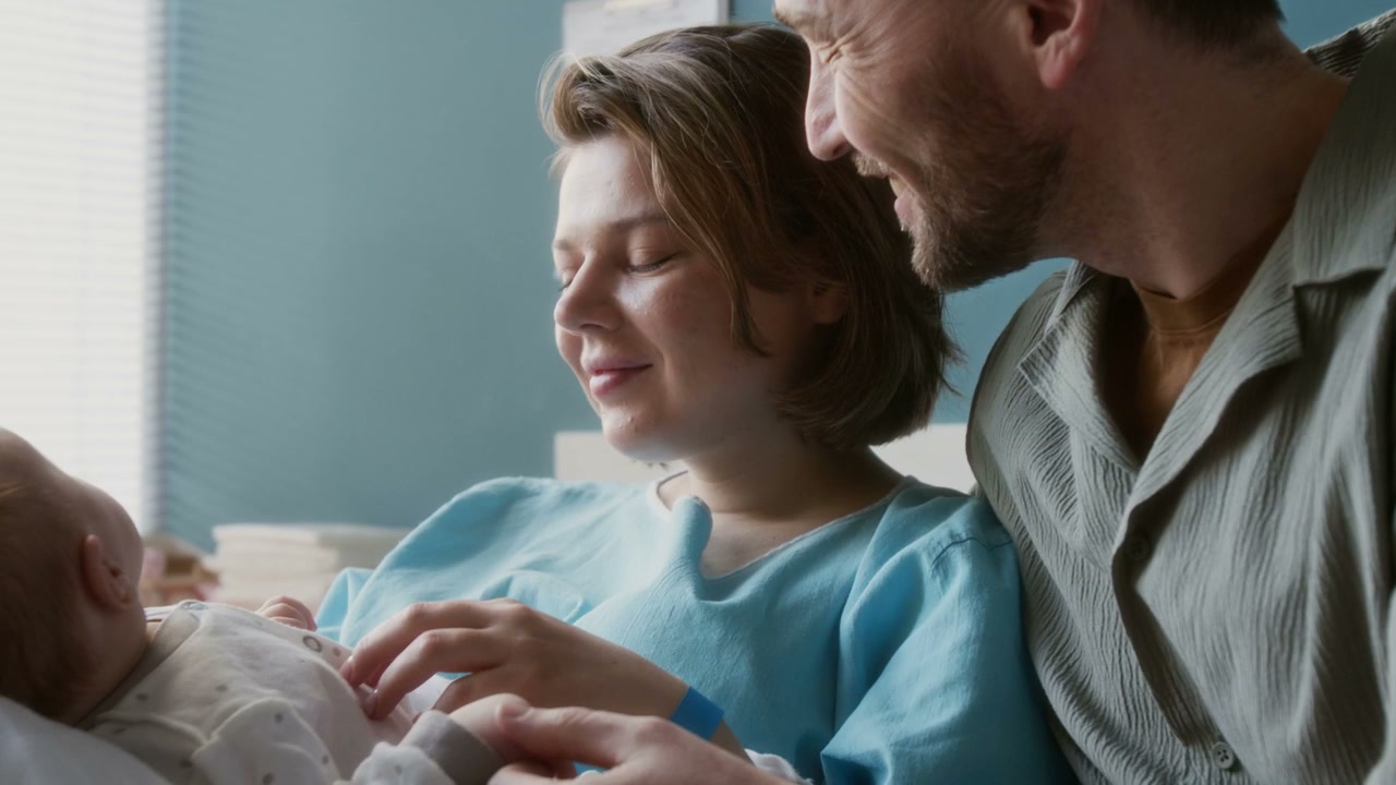 Smiling Parents With Newborn Baby In Hospital