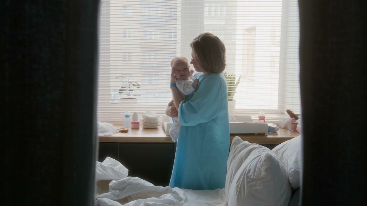 Mother Holds Newborn Baby in Hospital Room