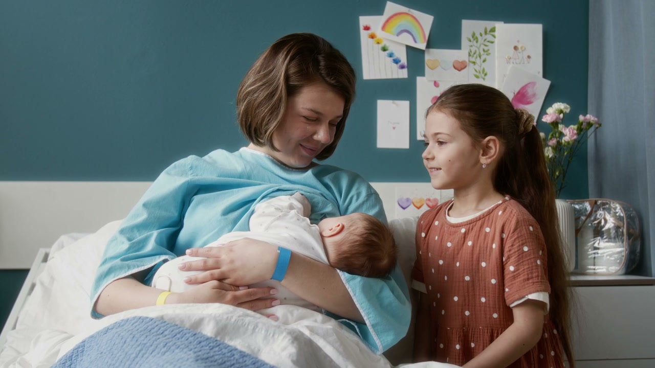 Mother Breastfeeding Newborn with Daughter in Hospital