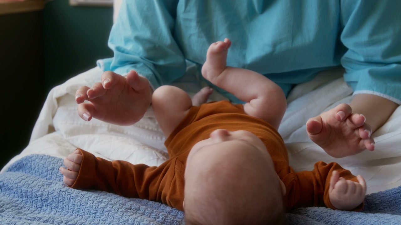 Mother Cuddling Newborn Baby in Hospital Bed