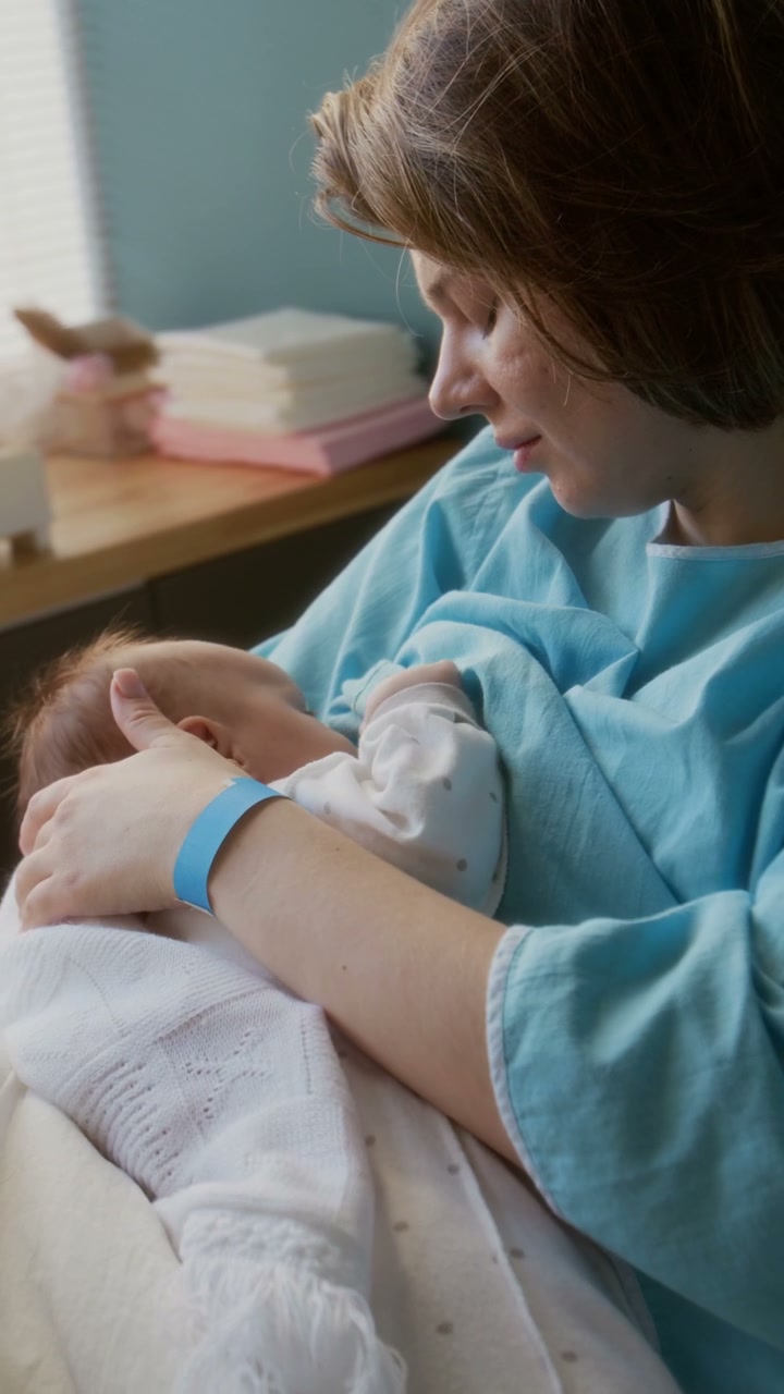 Mother Cradling Newborn Baby in Hospital