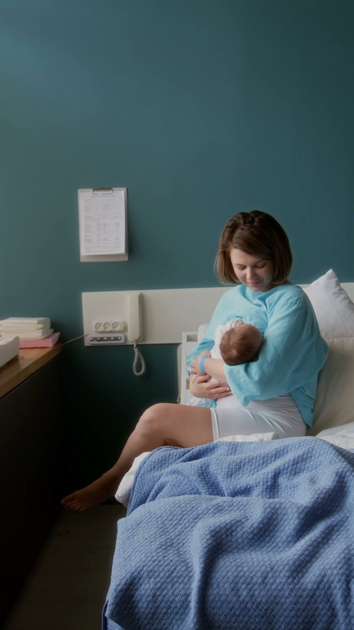 Mother Breastfeeding Newborn Baby in Hospital