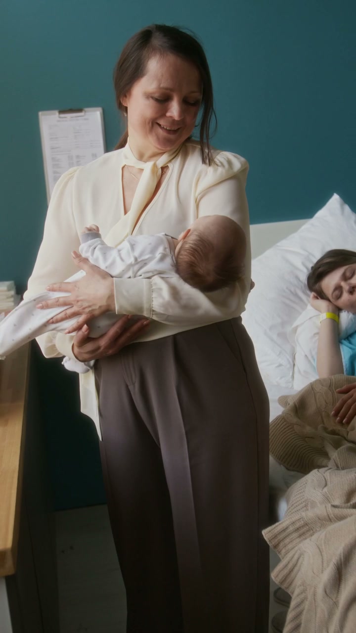 Grandmother Holding Newborn Baby in Hospital Room