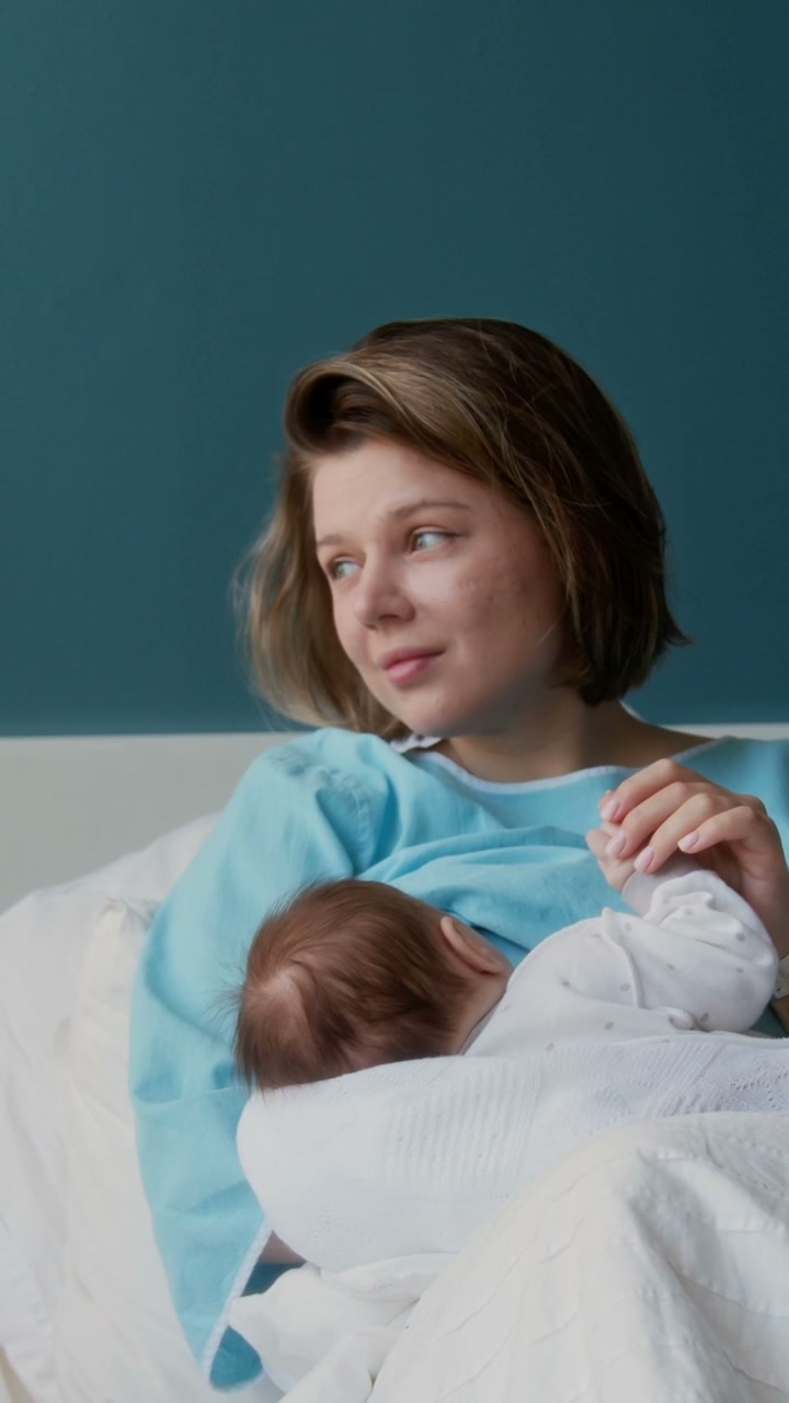 New Mother Breastfeeding Baby in Hospital Bed