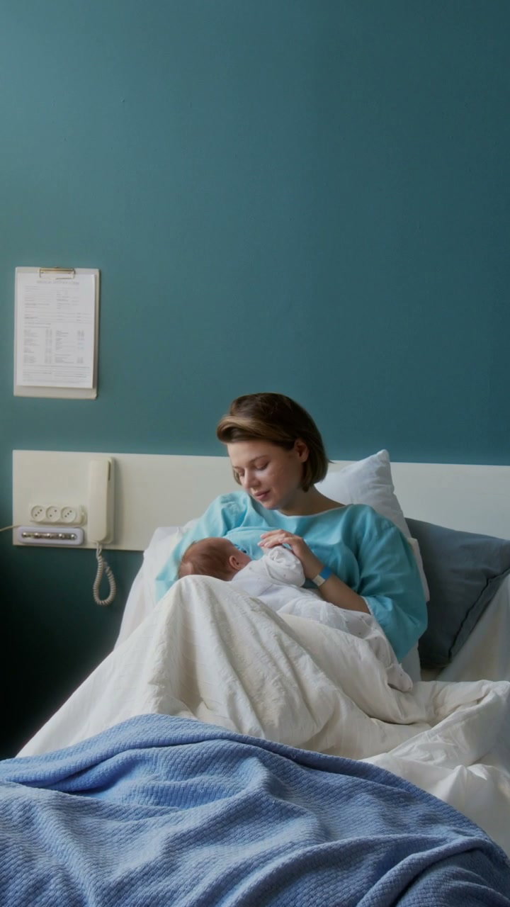 Mother Breastfeeding Newborn Baby in Hospital