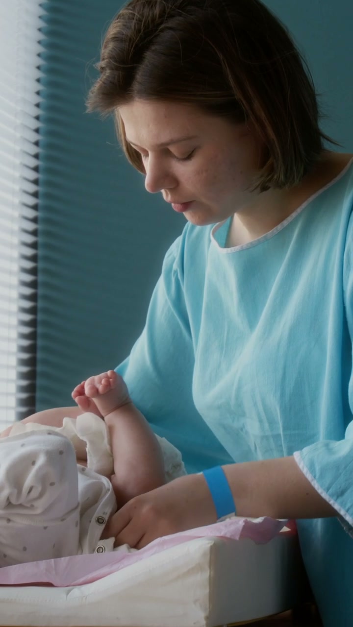 Mother Changing Baby's Diaper In Hospital