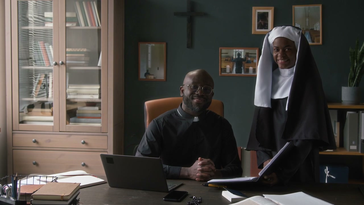 Nun and Priest Smiling at Desk