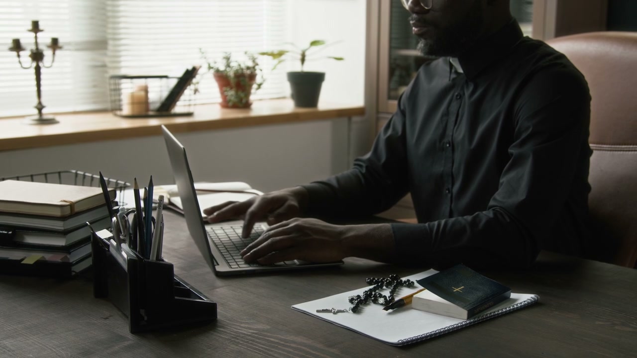 African American Priest Working on Laptop