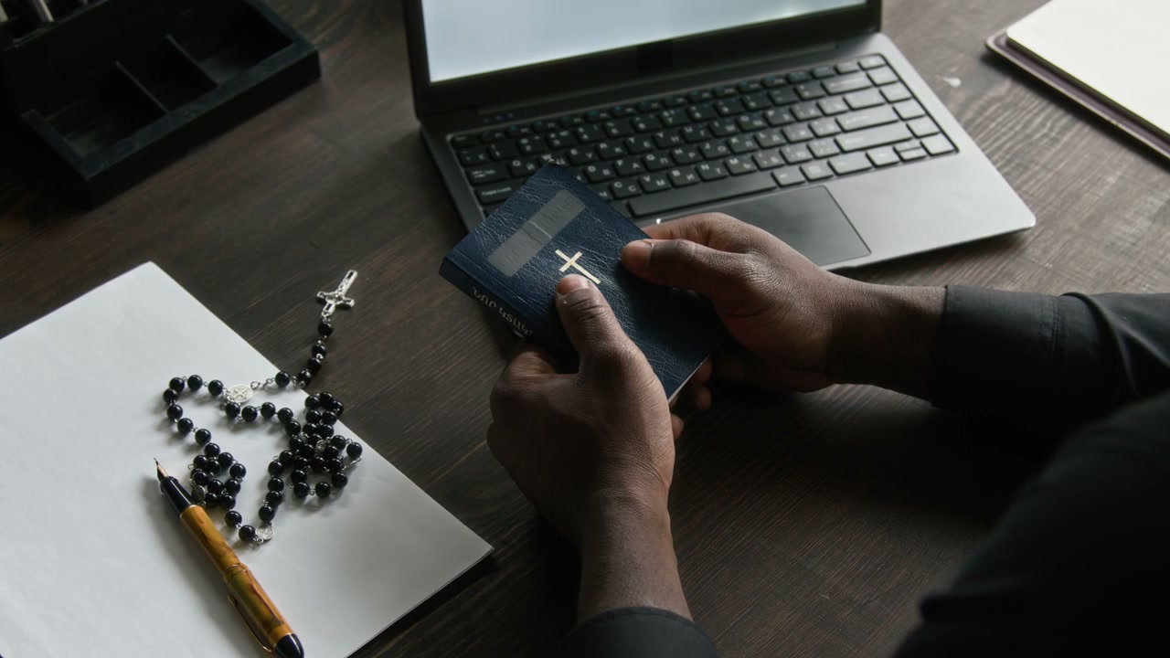 Priest Holding Bible at Desk
