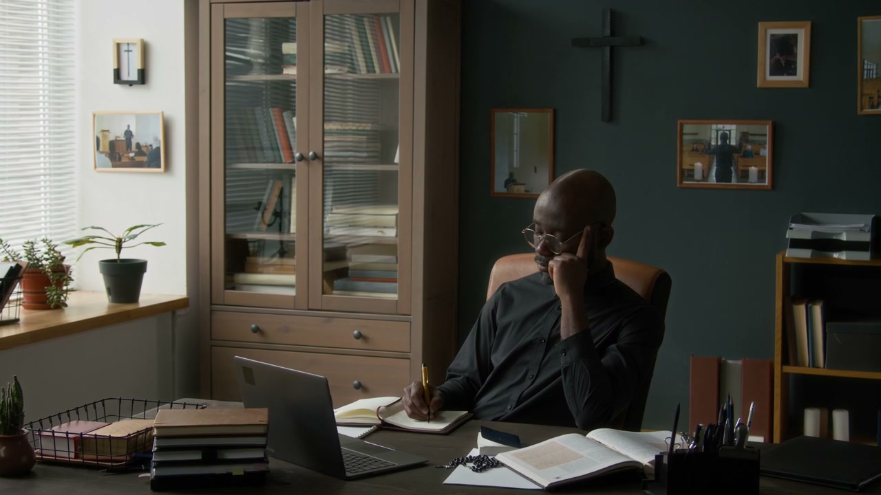 Clergyman Talking on Phone and Writing