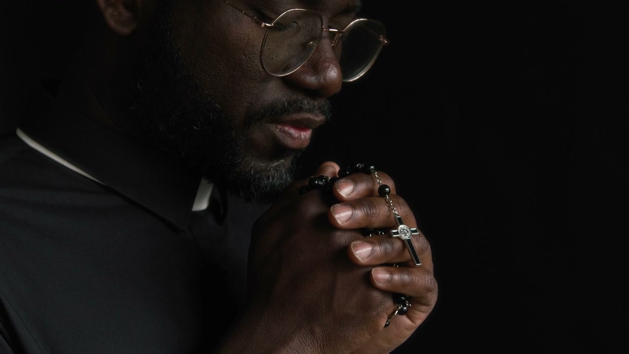 Close-Up of Priest Praying with Rosary Beads