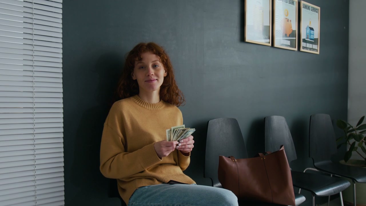 Smiling Woman Holding Cash in Bank Waiting Room