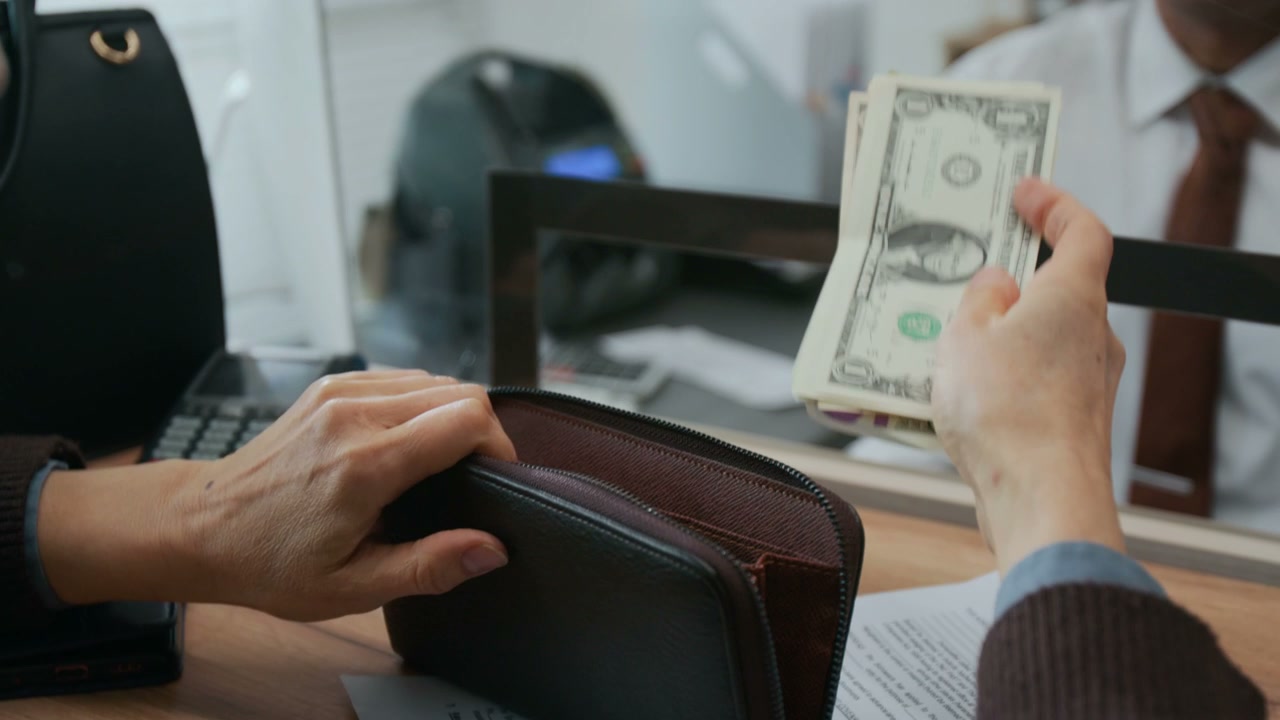 Customer Hands Cash to Bank Teller