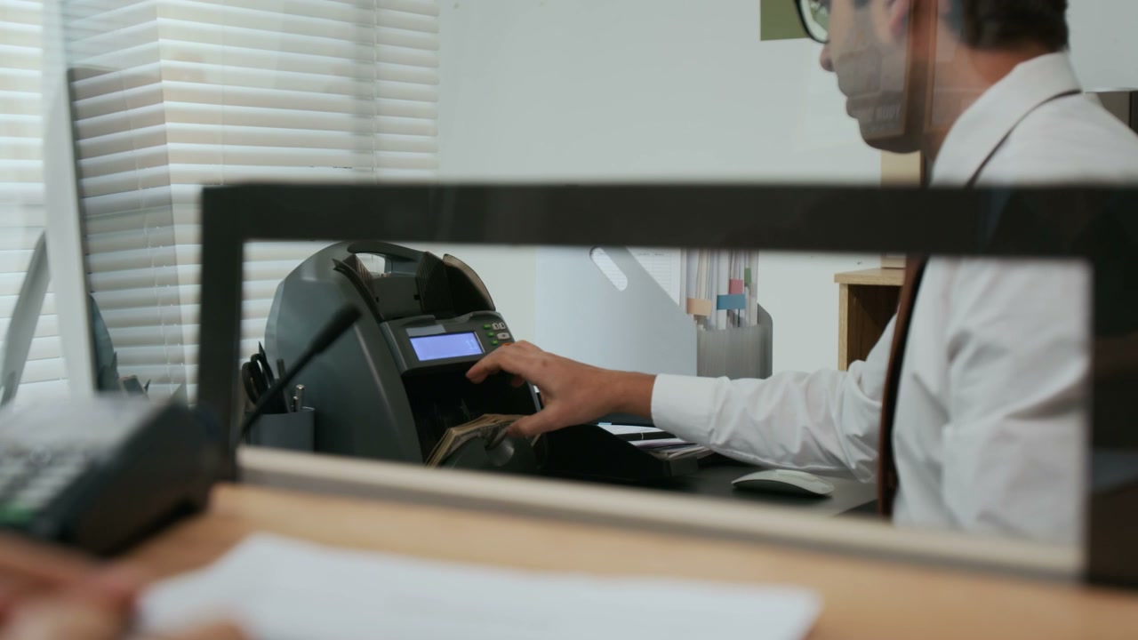 Bank Teller and Customer Handle Dollar Bills