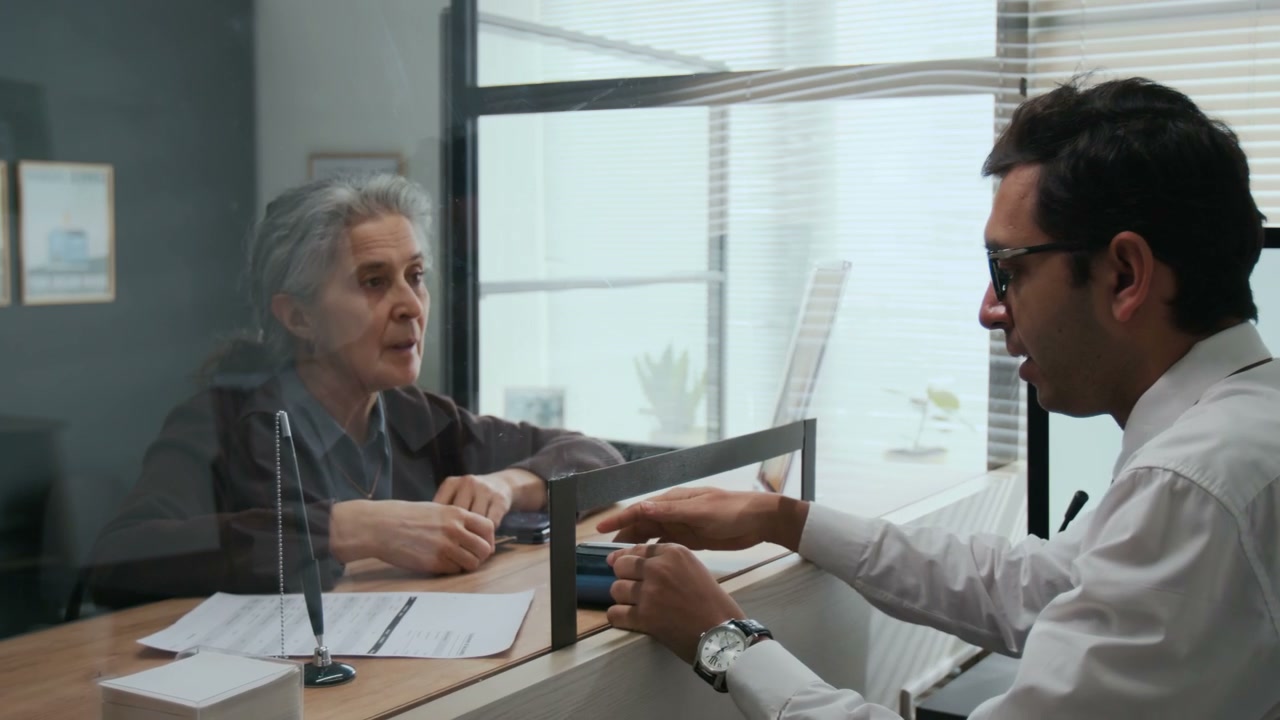 Senior Woman Making Card Payment at Bank Counter